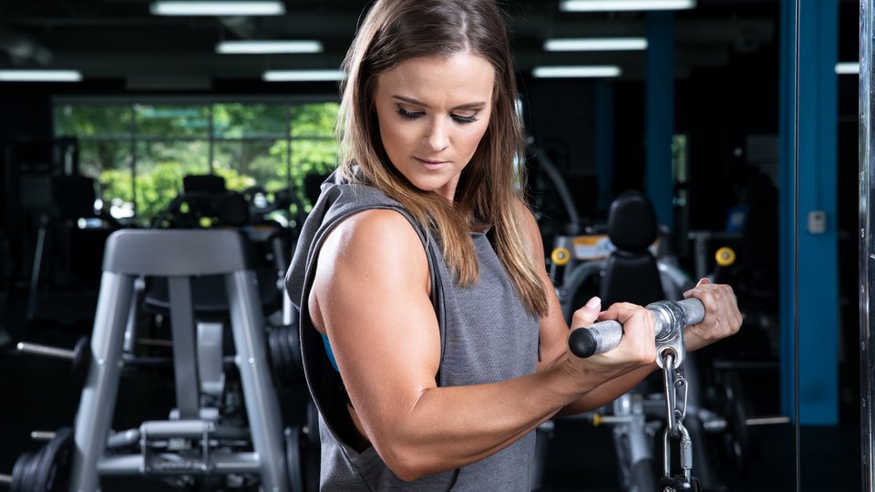 Woman exercise with dumbbells and working on her biceps at gym