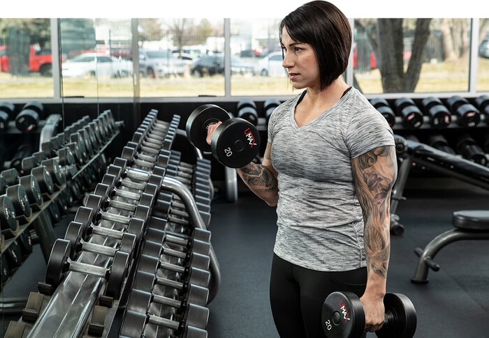 Female athlete performing a heavy dumbbell curl.