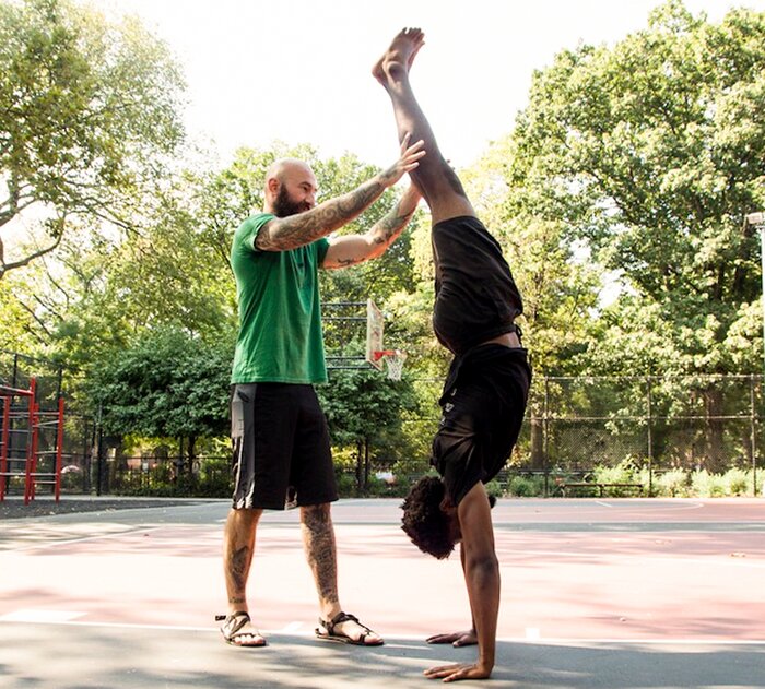 Al Kavadlo helping a client to a handstand. 