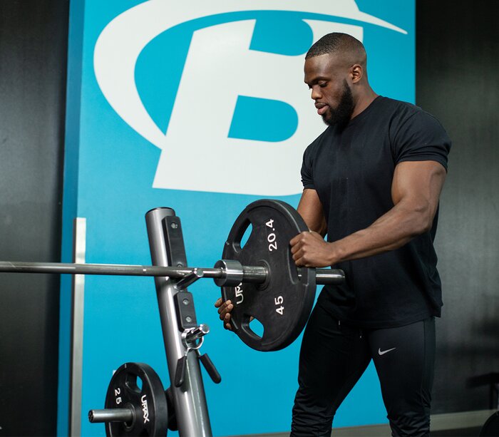 Adding a heavy dumbbell to the bar, preparing to bench press.